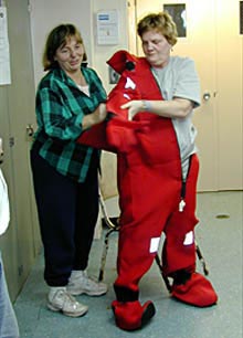 A member of the crew demonstrates how to put on the survival suit. This suit keeps people who have abandoned ship warm and dry.