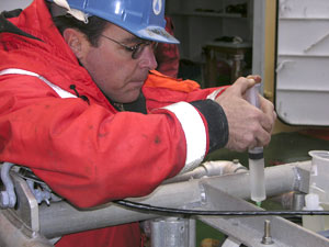 Erich injects tubes with oil to fill LAPIS� electrical junction box, to counteract the effects of water pressure at depth. Oil protects the electrical connections. (Photo by Larry Madin, WHOI)