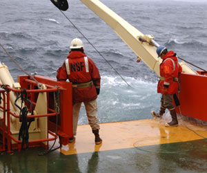 Erich Horgan, and Jamee Johnson, standing right at the side of the ship, find waves washing over the deck. (Photo by Kate Madin, WHOI)
