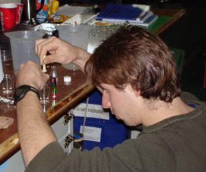 Brennan prepares a “sucrose density gradient” in a test tube. He makes water with sugar dissolved in it. First, he makes water with a lot of sugar dissolved in it (a high density of sugar) and uses one food coloring to identify it. 