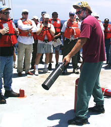 During the fire and boat drill, Dave Murline, the chief mate, demonstrates correct procedures for using a carbon dioxide fire extinguisher in the event of fires on board.