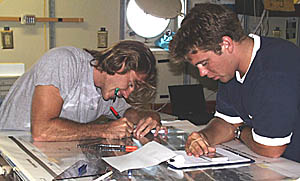 Greg Kurras (left) and Ben Wigham (right) compile observations from the first Argo II lowering that traversed about 35 kilometers of the axis of the Galapagos Rift valley. They are working on a light table and plotting the Argo II observations on top of the DSL-120 sonar maps. This way, they can relate the sonar imagery to the geology of the seafloor. 