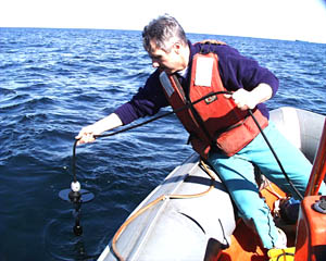 Dan Fornari lowers a hydrophone into the water to listen to and record sounds made by the dolphins and pilot whales. 