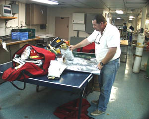 Rick Bean, the 3rd mate, checks and repacks the firefighting equipment after a Fire and Boat Drill. He is making sure that the equipment is in top condition and ready for use in an emergency. 
