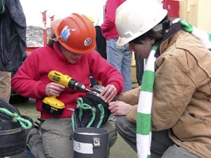 Brenna McLeod, graduate student from Trent University, Canada (left) and Lena Von Harbou use a drill to attach the net to the cod end. (Photo by K. Madin)