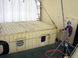 Marine Technician Peter Fitzgibbons holds a rope and guides the dive van through a tight opening into the ship�s hold. (Photo by L. Madin)