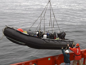 Seaman Elfren Prado (left) and Marine Projects Coordinator Eric Hutt brace the inflatable dive boat as it is lowered over the Gould�s side. (Photo L. Madin, WHOI) 