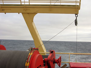 Looking toward the stern from the 0-2 deck, during the day. Wire from the winch is routed up through the block (pulley) before going down to connect to a net for towing.