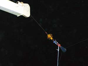 At around 10:30 p.m., the end of the crane wire (yellow square) is attached to a blue shackle, and then the red end of the temporary blockthe dark, teardrop-shaped pulley with the winch wire running through it. A white rope stabilizes the pulley.