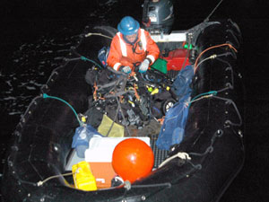 Marine Technician Peter Fitzgibbons checks the gear in the bottom of the inflatable dive boat before divers climb down from the ship.