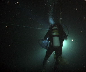 A diver hangs in the water, neutrally buoyant, illuminated by his diving lights. (Photo by Larry Madin, Woods Hole Oceanographic Institution)