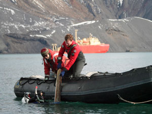 Brennan Phillips (in the water) lifts a whale rib left by earlier twentieth-century whalers and  found on the bottom of Whaler’s Bay up to Jeff Mercer and Jamee Johnson in the Zodiac. Trent University graduate student Brenna McLeod collected small shavings of bone for later DNA analysis. (Photo by Lens Von Harbou, Alfred Wegener Institute)