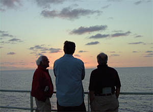 Dan Stuermer (middle), Lou Cabot (left) and Bob James watch the sunset as R/V Atlantis heads south at 13 knots on calm seas. 