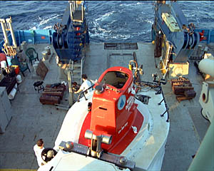 Alvin is pulled out of the hanger. The railroad tracks on the deck of the ship guide the dolly that the sub sits on so that Alvin is positioned directly below the A-frame for launching. 