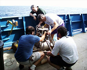  Dan, Jim, Jerry and Ed prepare the grab sampler for a quick trip to the seafloor. This device is designed to crash into the rocks on the seafloor and snap shut, thus "grabbing" a sample. After it has hit bottom, it is hauled back up to the deck of Atlantis. 