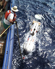 Bob Elder maintains control of the DSL-120 sonar by a tether line as it bobs at the surface, while the technicians in the Control Van run system tests on it. 