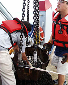 Erin Todd (right) and Jon Burgess unload lava samples recovered in Dredge #3 taken last night from the crest of the East Pacific Rise at a depth of 3200 meters. See if you can figure out how deep that is in feet (1 meter = 3.28 feet). Erin and Jon are wearing working life vests because the lines that go across the stern of the ship were removed to bring the dredge on board. Safety is important on board ship! [The answer to how deep the seafloor is at the location where Dredge #3 was taken is 10,496 feet]. 