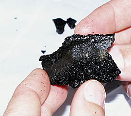 One of the small samples of volcanic glass recovered from about 3060 meters water depth on the East Pacific Rise axis near 3° 23.30’N and 102° 14.36’W. Note the very shiny surface of the lava. This forms when hot, molten rock is quenched (very rapidly chilled) when it comes in contact with the near-freezing seawater.