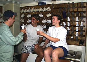 As we approach the Equator, some funny business is going on! There is a tradition among sailors that you have to be inducted into the honorable society of “Shellbacks” when you cross the Equator on a ship. People who have not crossed are called Pollywogs, like immature frogs or tadpoles. You can see that the drink glasses behind Greg Kurras and Julia Getsiv (both Pollywogs) have been replaced by medical specimen cups. Paul Johnson was looking for his glass and thinks he knows who was responsible for the mischief. Can you guess who it was that hid the glasses? 