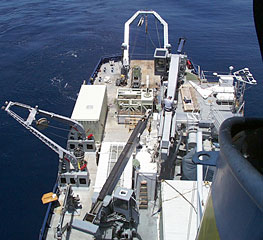 A view towards the stern of R/V Melville from the Crows Nest. The stern A-frame from which we tow DSL-120 and Argo II is at the top-middle of the photograph. The side A-frame on the starboard side is where the conductivity, temperature, depth (CTD) rosette system is lowered over the side. The ship’s smoke stack is at the bottom right of the photo. 