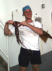 Tim Head, alias “Furtive Pollywog”, holds up a squid which the Shellbacks provided to serve as a measuring device (see next slide).
