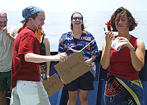 Tim Haskell (background), Peter Lean (left), Julia Getsiv (center) and Clare Williams (right, holding Feathers!), during one of the skits performed by the Pollywogs during the Equator Crossing Ceremony.
