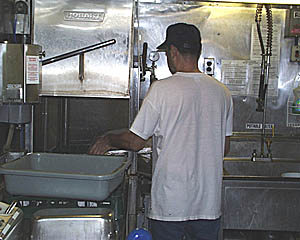 George loads the automatic dishwasher (large stainless steel cabinet to his left). The Cooks have make sure that all the plates, utensils, pots, pans, and other cookware are very well cleaned after each use. 