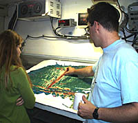 Dan points to where we are on the East Pacific Rise axis on a bathymetric map. He is explaining to Kate Gans about how the morphology, or shape, of the mid-ocean ridge is an indicator of how fast a ridge is spreading and whether it is volcanically active. When the ridge is wider and the crest is shallower it means that more lava has erupted there. 