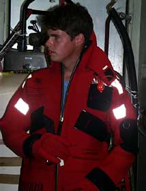 Third mate Adam Seamans dons a survival suit in a safety demonstration. The bright, buoyant rubber outfits act as a rescue beacon and one-person life raft. Used in case of ship evacuation, every person keeps one in their cabin.  