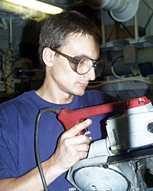  Third Assistant Engineer Piotr Marczak wears safety glasses while he cuts metal pieces needed to build a storage rack. 