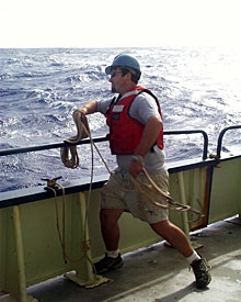 Seaman Mike Doherty heaves a grappling hook overboard to snag the current meter mooring. It was released from the seafloor after nine days on the bottom recording data. 