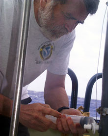 Chemist Marvin Lilley captures water from a collection bottle on the CTD for later analysis.  