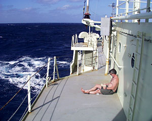 Chemist Eric Olson takes a break from his analyses by reading a book on the port 02 deck of Knorr.   