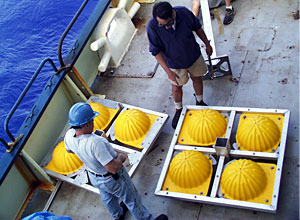 Bosun Al Hopkins (left) and Expedition Leader Andy Bowen discuss the plan for putting together the new elevator. The big yellow balls are the elevator’s floats.  