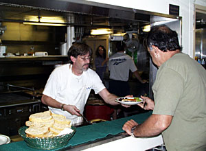  Cook Chris Poulin serves dinner to hungry Seaman Ed Graham. 