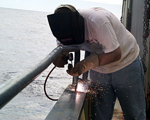 Seaman Mike Doherty welds a cleat on the starboard rail of Knorr. Crew members use cleats to control lines that restrain equipment while it is launched and recovered.  