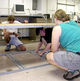  The laboratories on R/V Revelle can be easily changed to suit different science programs. Here Kate Buckman (right), Rhian Waller (under the table), and Ben Grosser build a bench in the Main Lab.  
