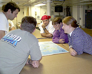 Todd Ericksen, Josh Curtice, Steve Volpe, Rhian Waller, and Kate Buckman (clockwise order), plan their site seeing and look over a map of the Galapagos in preparation for landing there on Sunday. 