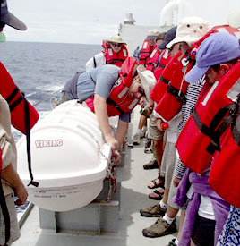  The whole ship's company participated in fire and boat drills after lunch to insure that everyone knows what to do in an emergency. Here Eric Wakeman, the first mate, demonstrates how to deploy a life raft while the scientists look on.
