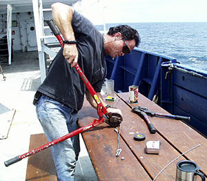 James Pearson terminates small wires as part of his daily work aboard the ship.  