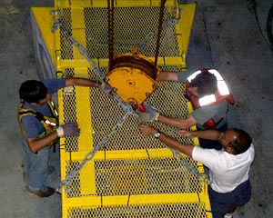 Steve Tottori, Josh Curtice and JJ Becker (clockwise) attach the crane hook to the camera so that it can be moved beneath the A-frame, ready for deployment.  