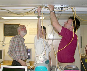 Al Bradley (left), Stace Beaulieu (center), and Craig McLean (right) run cables to connect computers to the ship's network. 