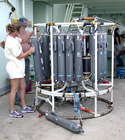 Christina Courcier and Bosun Wayne Bailey check the water-sampling bottles on the rosette sampler in preparation for a hydrocast at the Rose Garden hydrothermal vent site tonight.