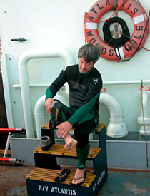 Able Seaman Patrick Hennessy dons his wetsuit just before Alvin was set to dive. Two swimmers always accompany the submarine before it goes underwater, and when it re-surfaces. They attach the lines that are used when Alvin is deployed and retrieved. 