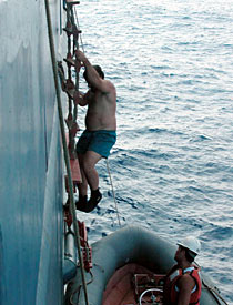 After the first Alvin dive of the cruise to take up the entire day, Able Seaman Jerry Graham climbs into the Avon while Ordinary Seaman Raul Martinez looks on. The Avon drops the swimmers off at the sub once it has risen to the surface, and then helps bring it back to R/V Atlantis. 