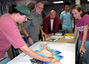 During today's science meeting, Chief Scientist Jess Adkins points to a potential dive site on a map of Muir Seamount. The science meetings are a time to review the day's dive, discuss how data analysis is going, air questions, and plan future operations. 