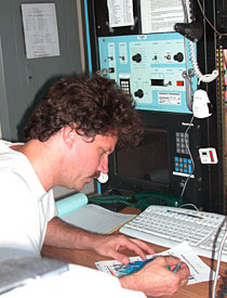 Chief Alvin pilot BLee Williams mans the top lab on the ship during a submersible dive. The top lab pilot maintains contact with Alvin, keeps track of its course, and monitors surface weather conditions. 