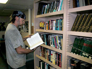 Oiler Dan Kreidler takes a break from the noisy work of the engine room, perusing a book in the ship library.  