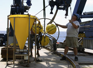 Bosun Wayne Bailey helps biologists prepare for tonight’s deployment of the cone-shaped larval trap. The round balls next to the trap are used as floats that keep the trap upright while it is anchored near the seafloor. 