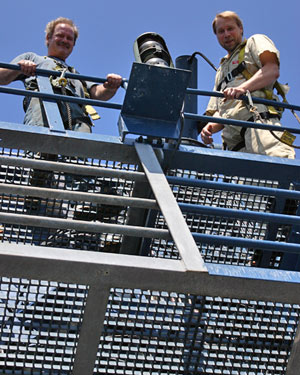 Oiler Allen Farrington (left) and engineer Keith Strand wear safety harnesses when working 60 feet (20 meters) above the deck doing weekly maintenance on the ship’s A-frame, used for launching and recovering Alvin each day. 